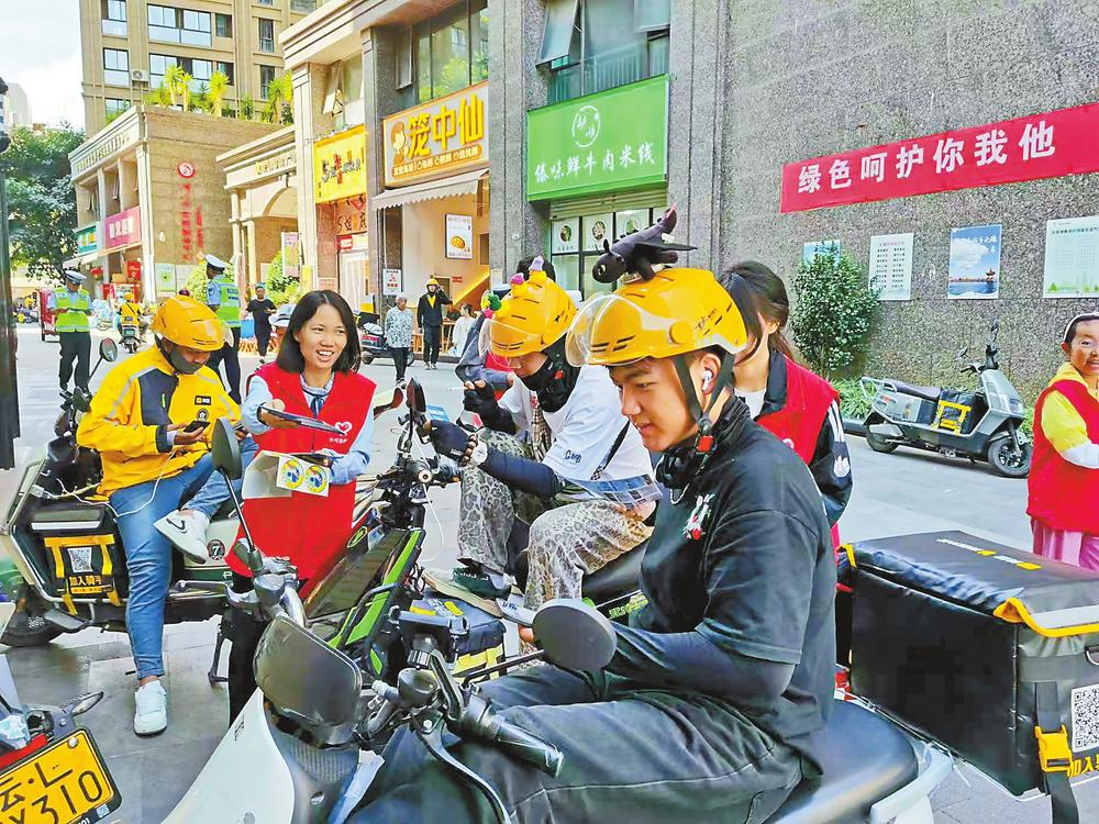 社区志愿服务者向外卖骑手宣传“暖新驿站”。记者 段苏航 摄